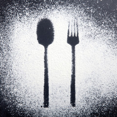 Spoon and fork silhouette made with flour on the dark texture background,