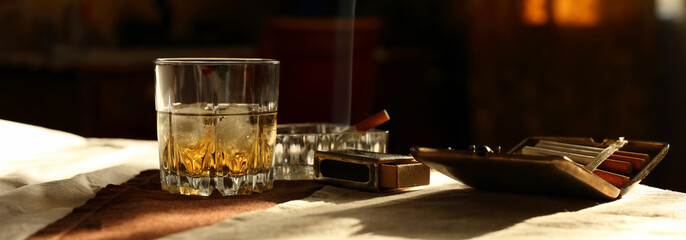 Panorama still life with a glass of whiskey and a cigarette in retro style