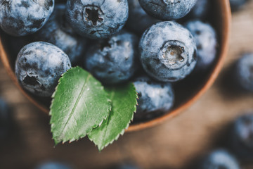 Freshly picked blueberries in wooden bowl on wooden background. Healthy eating and nutrition.