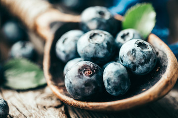 Blueberries in wooden spoon on old wood table. Healthy eating and nutrition concept.