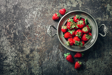 Freshly picked Strawberry in bowl on dark metal background. Healthy eating and nutrition.