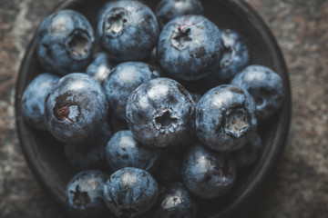 Freshly picked blueberries in  bowl on old metal background. Healthy eating and nutrition.