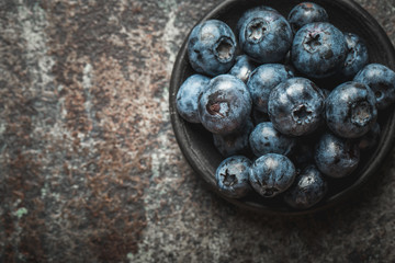 Freshly picked blueberries in  bowl on old metal background. Healthy eating and nutrition.