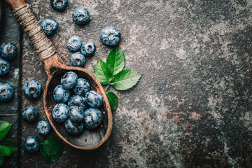 Blueberries in wooden spoon on old dark metal table. Healthy eating and nutrition concept.