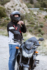 Fototapeta na wymiar Young male biker putting on his helmet to drive his motorbike