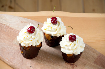Three sweet cupcakes with creme and cherry
