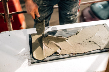 Details of worker using mortar for stone installation.Industrial worker, builder working on stone tiles.