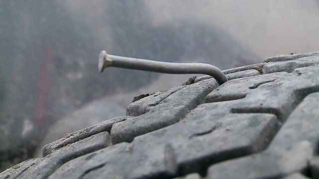 An extreme close up shot of a bent metallic  nail on a tyre