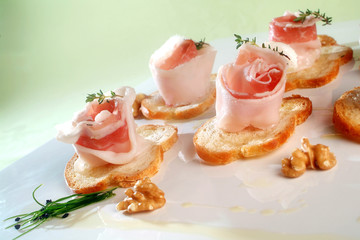 Italian food recipes, spiced with herbs Colonnata lard rolls on toasted bread slices