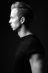 Studio shot of young handsome man against gray background in bla
