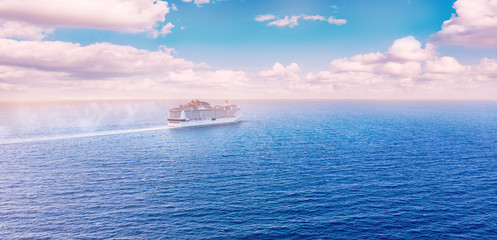 White cruise liner floats across blue sea into sunset. Concept travel. Aerial view