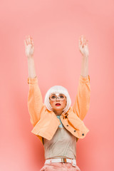 fashionable model in white wig and sunglasses posing like a doll isolated on pink