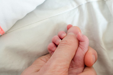 Hand of newborn baby holding male adults finger. Concept of help and family. Father holding hand.