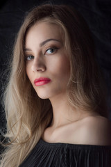 Naklejka premium Beautiful ,young blonde with bright red lips and expressive eyes in a black jumpsuit. Beauty portrait of a girl. Emotional and bright appearance. Fashion portrait of a woman.