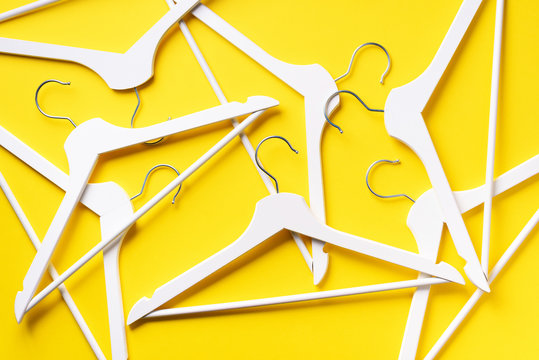 White clothes hangers on yellow background with copy space. Flat lay. Top view. Minimalism style. Creative layout. Fashion, store sale, shopping concept. Banner for feminine blog
