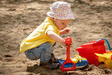 adorable blond caucasian baby playing on sand box