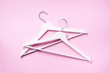 White clothes hangers on pink background with copy space. Flat lay. Top view. Minimalism style. Creative layout. Fashion, store sale, shopping concept. Banner for feminine blog