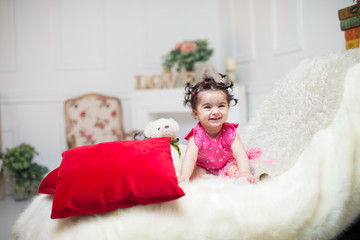 Happy smiling sweet baby girl sitting on sofa with bear toy