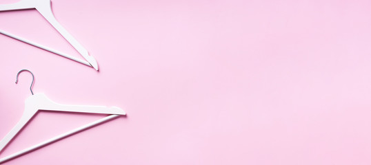 Top view of white clothes hangers on pink background with copy space. Flat lay. Minimalism style. Creative layout. Fashion, store sale, shopping concept. Banner for feminine blog