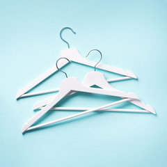 Top view of white clothes hangers on blue background with copy space. Flat lay. Minimalism style. Creative layout. Fashion, store sale, shopping concept. Banner for feminine blog