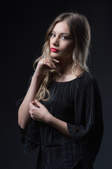 Beautiful ,young blonde with bright red lips and expressive eyes in a black jumpsuit. Beauty portrait of a girl. Emotional and bright appearance. Fashion portrait of a woman.