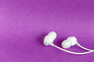 White earbuds on purple colorful background with copy space for text
