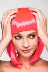 attractive young woman in pink wig isolated on grey