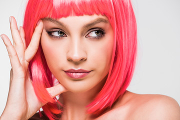 thoughtful young woman in pink wig isolated on grey