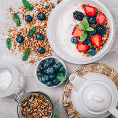 Healthy breakfast with granola, yogurt, fruits, berries on white background.