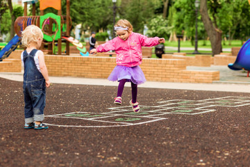 Active little girl play in hopscotch and jump on playground