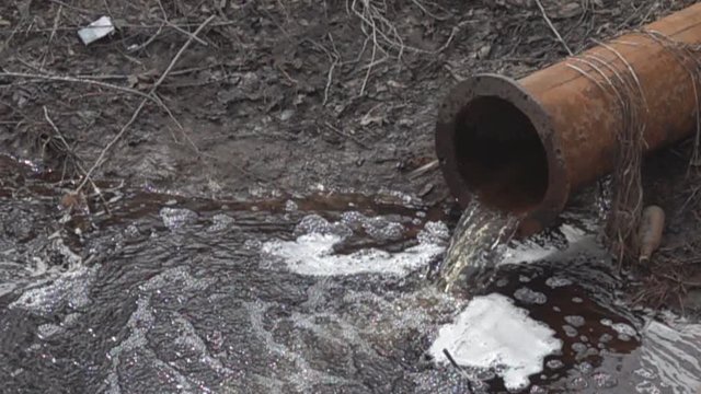 Chemically dirty water gushing from a large rusty pipe in the river, formed foam. Water pollution. Super slow motion 1000 fps