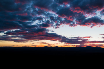 Purple and pink outlines beautiful clouds at sunset over a mountain range silhouetted against the sky - Jemez Mountains near Santa Fe, New Mexico