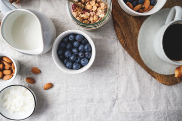 Top view of breakfast table with coffee,  granola, nuts, berries and milk. Flat lay, healthy eating concept, copy space.