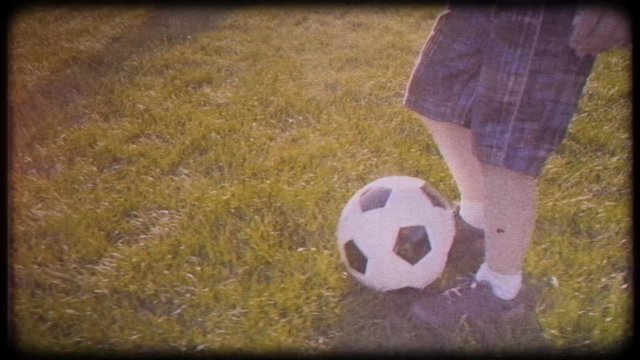Boy playing soccer ball. Child with the ball runs through the green grass. Family video. Archived video. Old film. Famous footballer in childhood. Children's sport. Family holiday.  Training. Happy