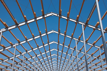 The metal frame of the building on a reinforced concrete base. The use of materials from metal and concrete in modern construction.