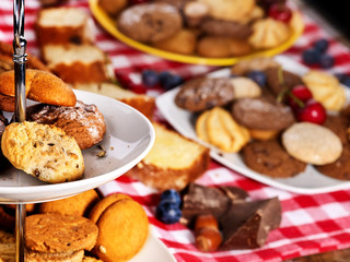 Cookies and sand biscuit on tier cake stand with blueberry chocolate on kitchen on picnic table in rustic natural style. Composition of confectionery.