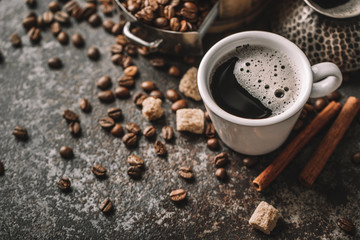 Coffee cup and coffee beans on dark stone background.