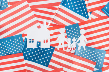 Obraz premium top view of white paper cut house and family on american flags background