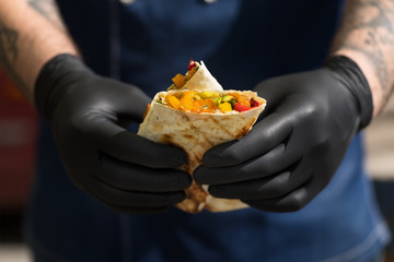 Shawarma - the best street food . Eastern cuisine. Meat and vegetables - tasty and healthy . Close- up of a man's hands.