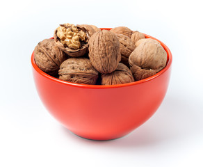 pile of walnuts lying in an orange bowl on a white background