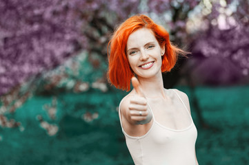 Confident happy female person showing on the outstretched hand a thumb up sign