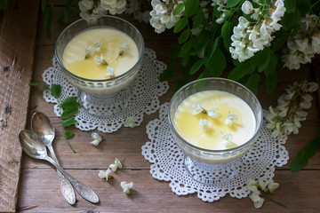 Panna cotta with robinia flavor, served with honey and white Robinia flowers. Rustic style.