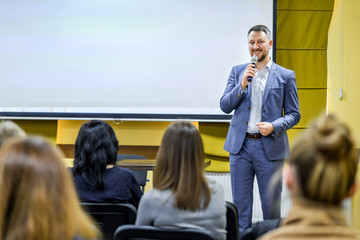 Business leader male conducts a lecture with a smile on his face during the conference. Man in...