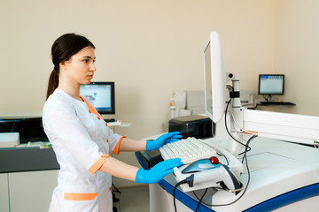 Professional laboratory technician is holding a vial near the automated medical machine. Woman...