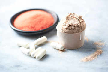 Scoop of Whey Protein, Beta-alanine capsules and Creatine Powder. Sport nutrition. Stone background. Copy space