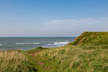 Looking out over grass covered cliffs towards the ocean, on the Isle of Wight coast