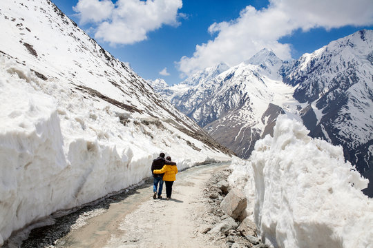 Couple walking trough ice wall bound road in high altitude Himalaya