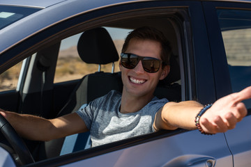 happy young man driving a rented car in the desert of israel