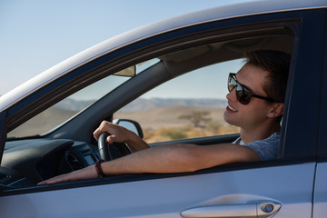Naklejka premium happy young man driving a rented car in the desert of israel