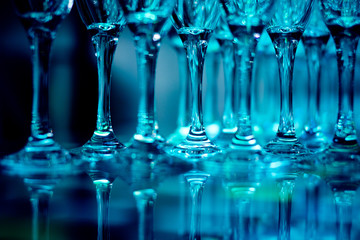 Close-up of coupe glasses with reflections in blue light on blurred background. Restaurant atmosphere